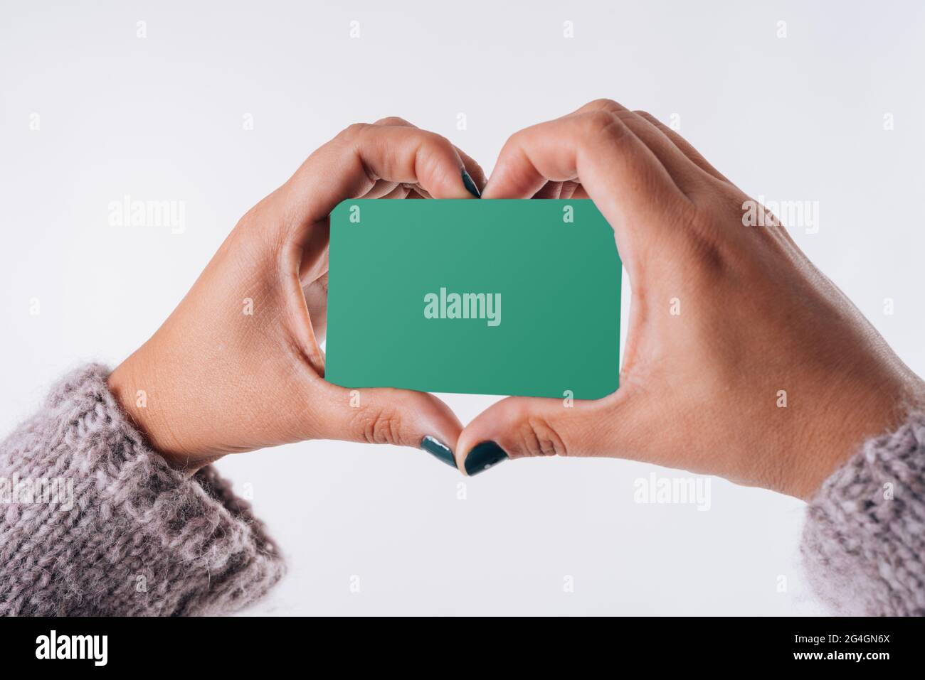 Un coeur formé avec les mains d'une femme qui a une carte d'achat. Concept commercial Banque D'Images