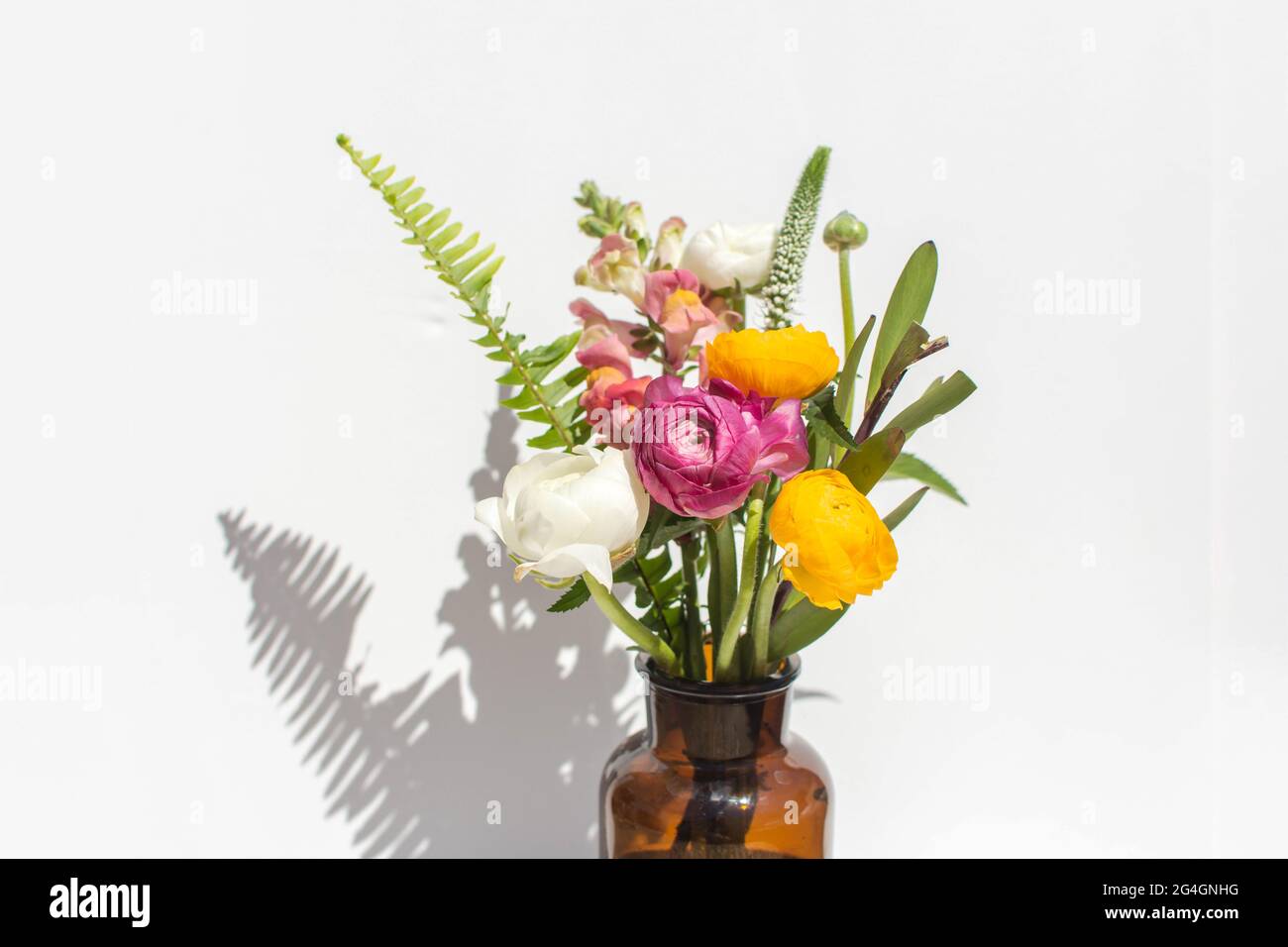 Bouquet d'été lumineux dans un vase ambre sur fond de marbre blanc. La vie éditoriale est encore sous un soleil éclatant. Banque D'Images