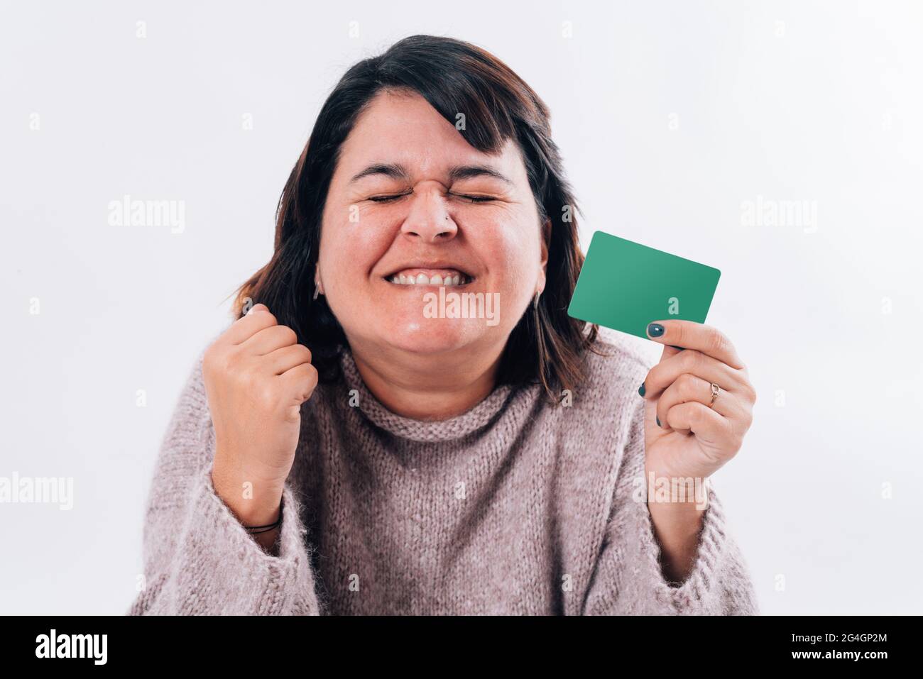 Femme exagérément heureuse qui se serre les yeux avec une carte d'achat en ligne dans sa main. Concept commercial Banque D'Images
