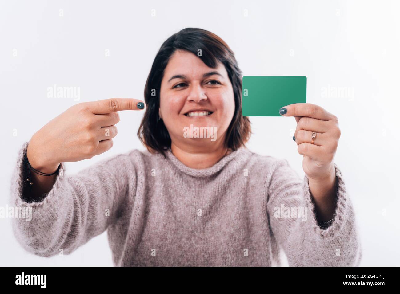 Portrait d'une femme pointant une carte de crédit contente sur fond blanc. Concept d'achat en ligne Banque D'Images