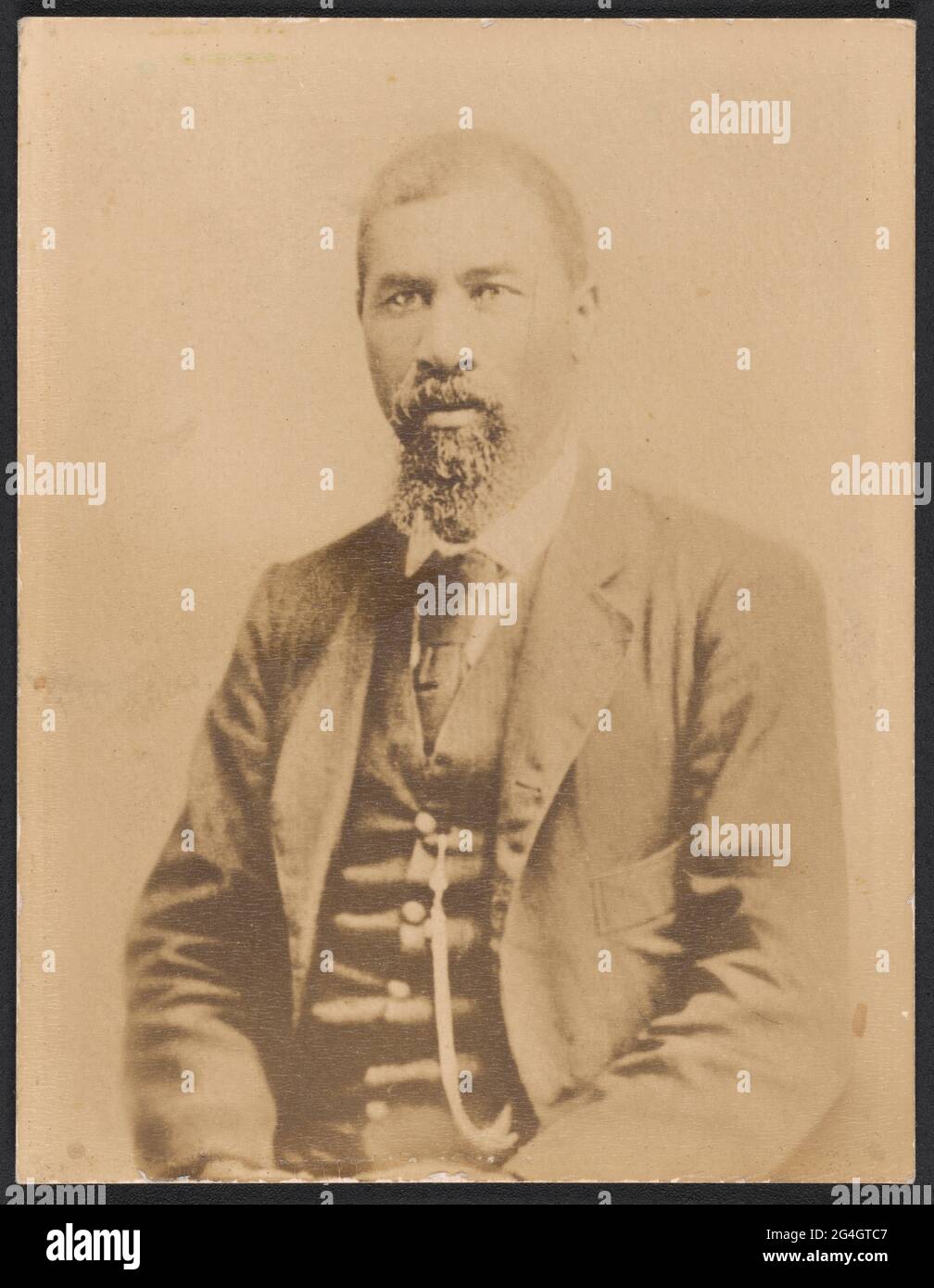 Une photographie brunâtre imprimée sur du papier texturé de Nelson Jordan. Jordan est assis dans un portrait de trois quarts avec son corps tourné légèrement vers la gauche, mais face à l'appareil photo. Il porte une combinaison de trois pièces de couleur foncée, une cravate foncée, une montre de poche, et a une barbe et une moustache. Son nom est écrit à la main en graphite sur le verso. Banque D'Images