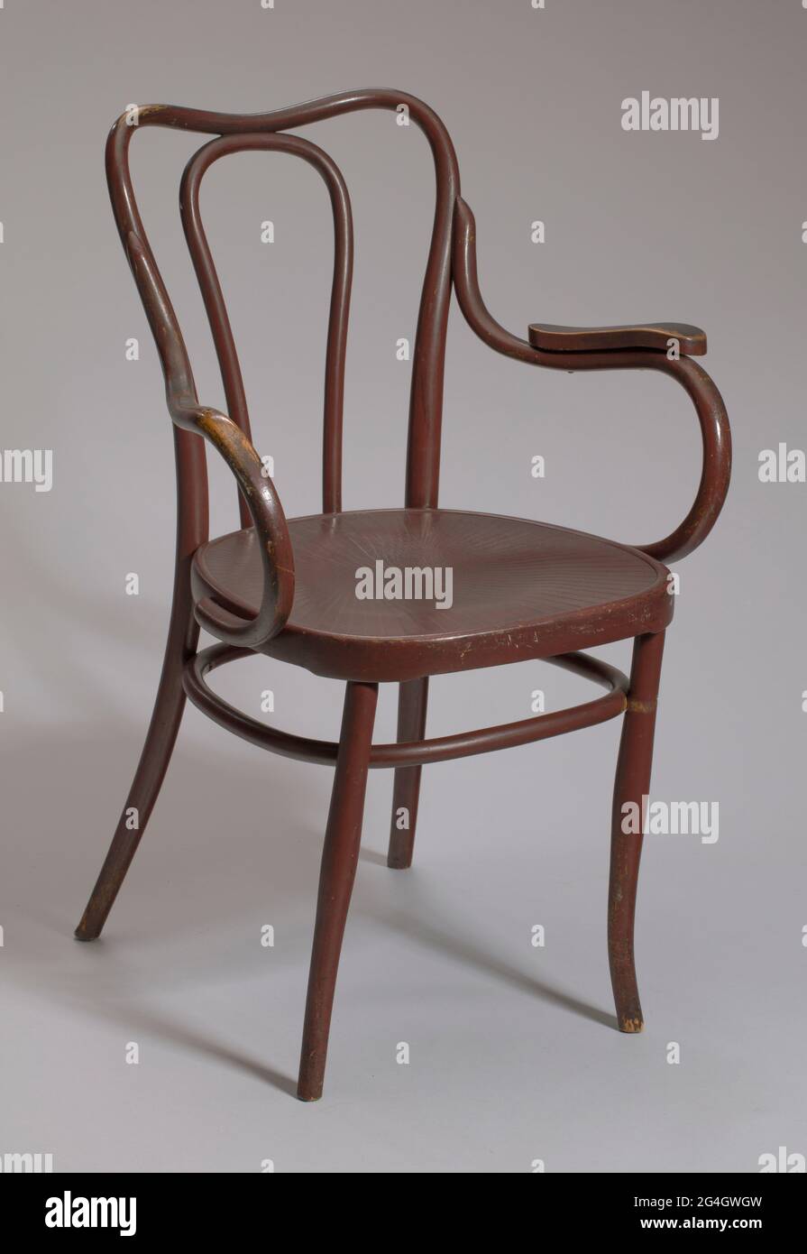 Fauteuil en bois de bentwood à quatre pattes. Chaise recouverte d'une  peinture ou d'une finition rouge-marron foncé. La chaise est ronde avec des  rebords sculptés peu profonds sur le dessus du siège.