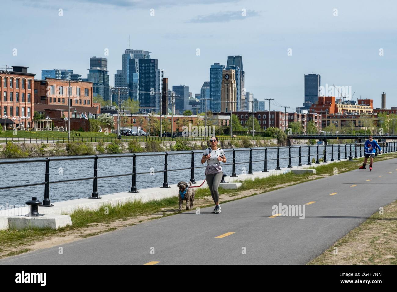 Montréal, CA - 15 mai 2021 : une femme qui court sur la piste cyclable du canal de Lachine, avec une ligne d’horizon en arrière-plan. Banque D'Images