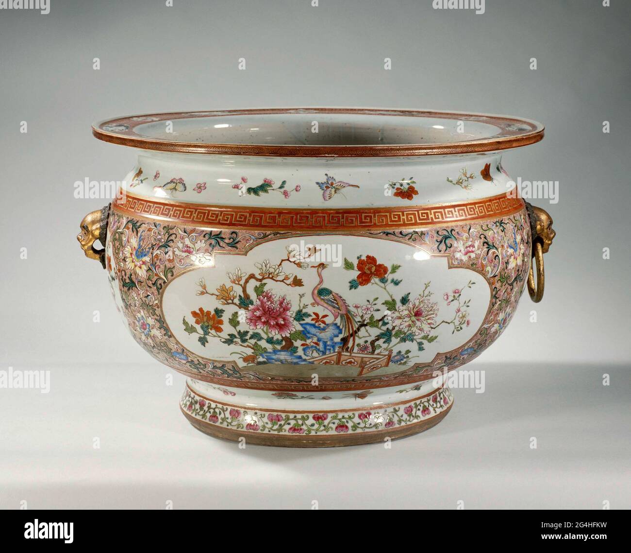 . Bol à poisson en porcelaine, peint sur le glaçage en bleu, rouge, rose, vert, jaune, noir et or. Le mur est recouvert d'un motif en spirale avec des boissons florales. Deux grandes cartouilles avec un faisan sur une roche avec une clôture et des plantes à fleurs (Prunus, Peony, Magnolia, Aster). Sur le mur, deux têtes de lion modélisées en biscuit avec un anneau; il y a un plus petit, autour de cartouche avec des boissons florales. Au-dessus et au-dessous de cette décoration un groupe avec un motif Meander. Sur le cou et au-dessus du pied, les branches de fleurs et les papillons sont lâches. Le pied avec un groupe de boissons aux fleurs. Sur l'interrupteur de serviette de bord Banque D'Images