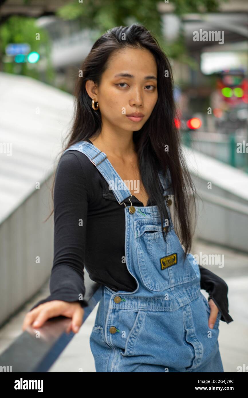 Une fille asiatique en ville s'appuie sur les chemins de fer Banque D'Images