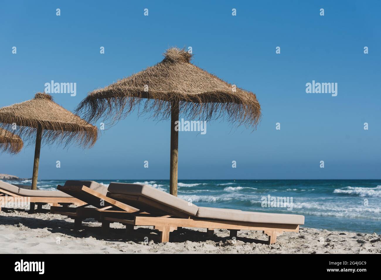 Chaises longues et parasols en paille sur la magnifique île de Formentera  en Espagne Photo Stock - Alamy
