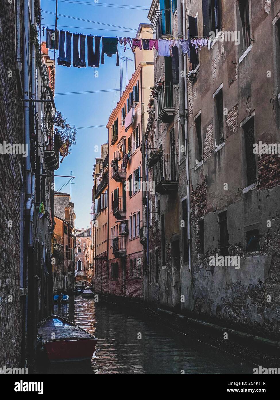 Petite rue pittoresque du canal à Venise avec un bateau et séchage des vêtements au soleil Banque D'Images