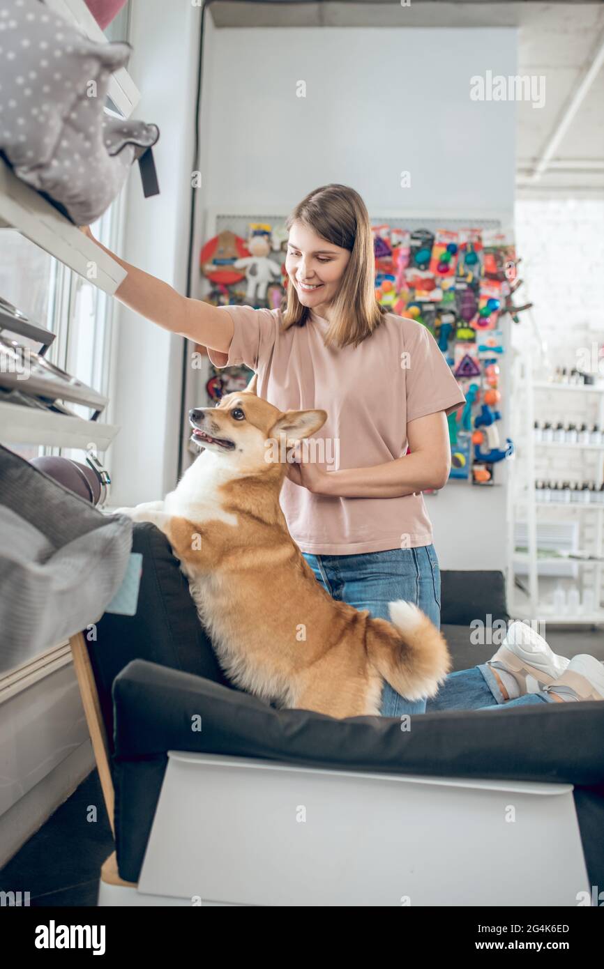 Une fille souriante choisissant des accessoires pour animaux dans une boutique d'animaux de compagnie Banque D'Images