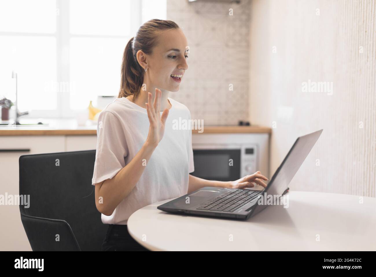 Jeune femme travaillant sur un ordinateur portable dans la cuisine. Femme indépendante travaillant en ligne Banque D'Images