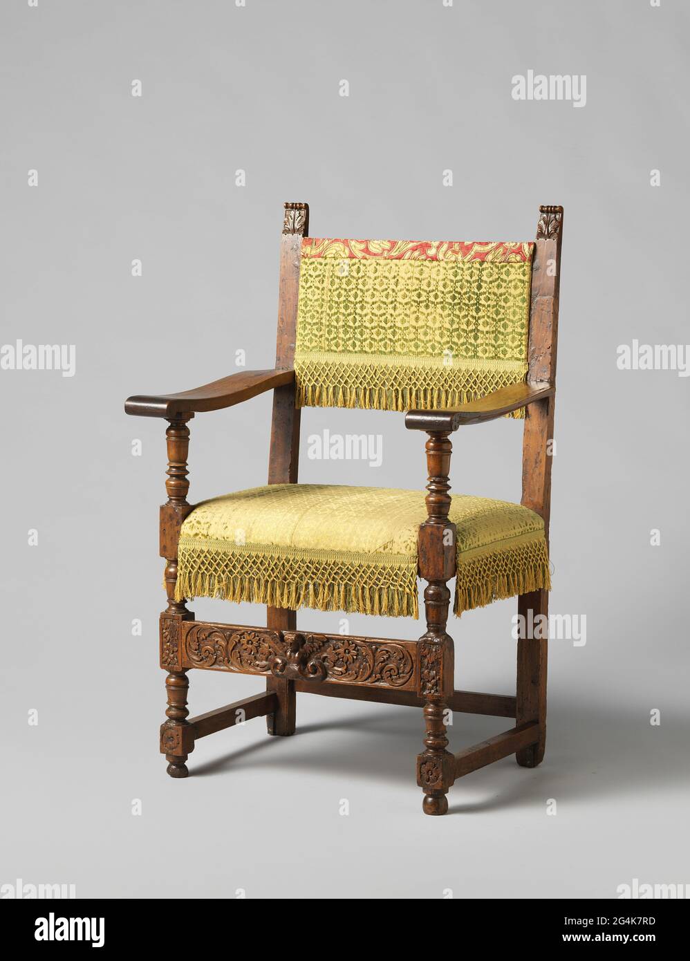 Fauteuil en noyer. Fauteuil en noyer appartenant à une ambuele de quatre fauteuils. Les jambes avant et les jambes de bras montrent la position initiale et l'articulation. Les maisons aux motifs feuilles sont reliées par un arrangement plat avec des réflexions de feuilles pellées, entre lesquelles une figure de femmes ailées dont l'extrémité inférieure passe en volutes dégénérés. Les larges accoudoirs plats légèrement cicatrisé se terminent par des volutes de feuilles fermées. Les styles de dos se terminent par des volutes de feuilles ratées. La garniture damassé d'origine est recouverte d'un tissu ancien d'une cavité. Banque D'Images