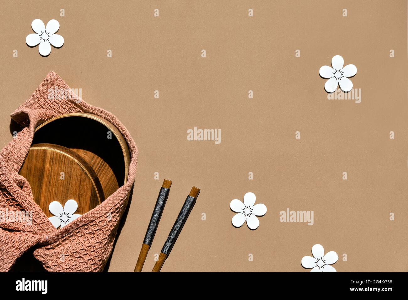 Coffret repas zéro déchet sur fond de papier brun, fleurs déco. Boîte à lunch, baguettes en bois enveloppées de tissu de furoshiki. Pose à plat Banque D'Images