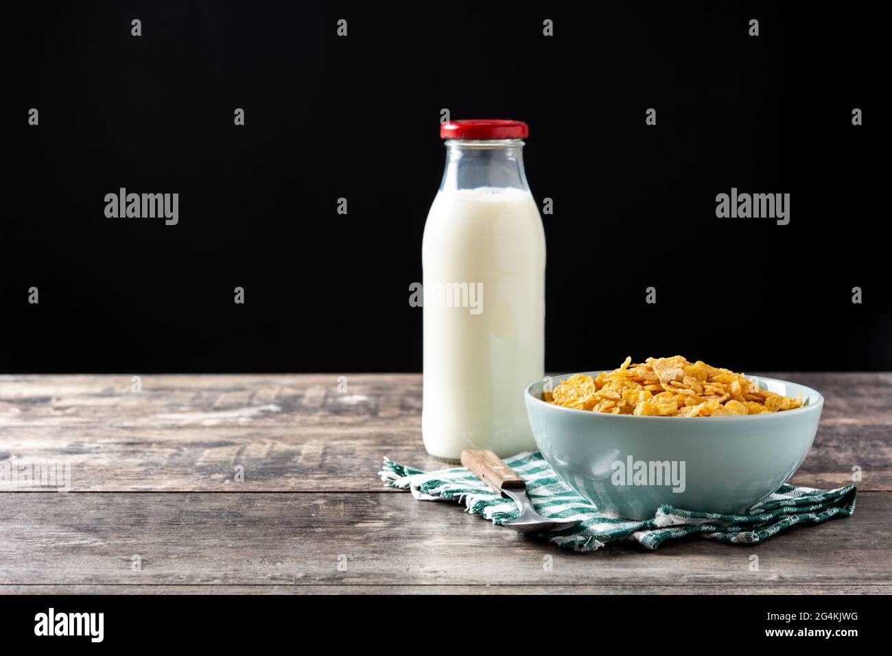Flocons de maïs dans un bol bleu et bouteille de lait table en bois Banque D'Images