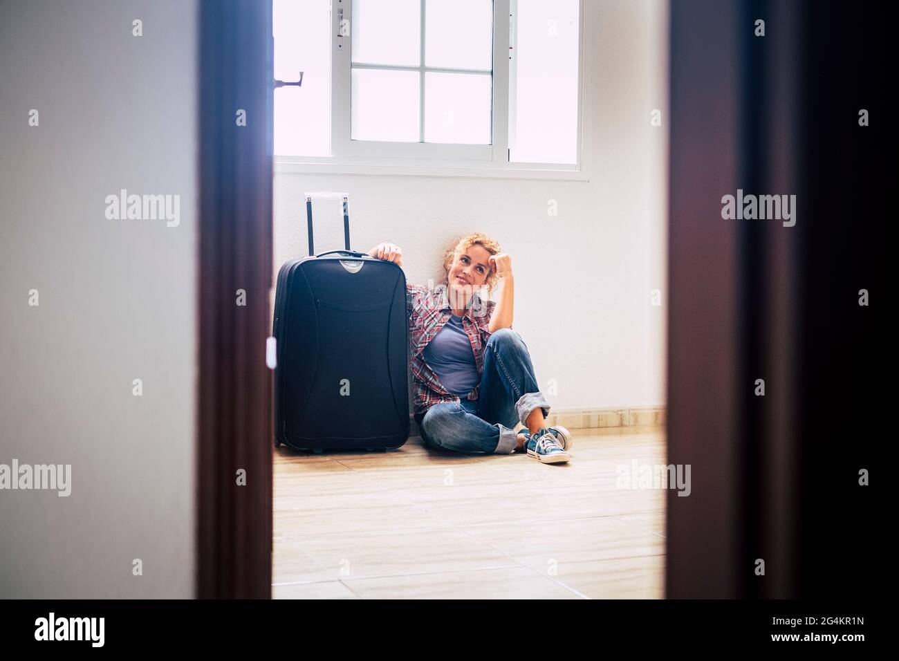Une femme s'assoit seule à l'intérieur de la maison vide avec des bagages - nouvelle maison hypothécaire acheteurs personnes concept - immobilier femme dame relaxant intérieur Banque D'Images