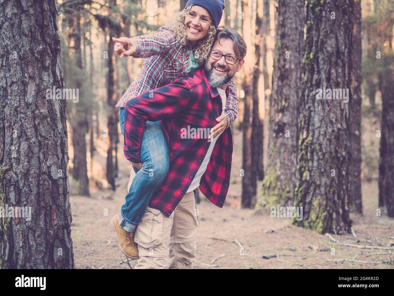 Joyeux et amusant couple caucasien ayant le piggyback tout en marchant sur le sentier dans les bois. Concept d'aventure dans la nature - jeune homme et femme adulte enjo Banque D'Images