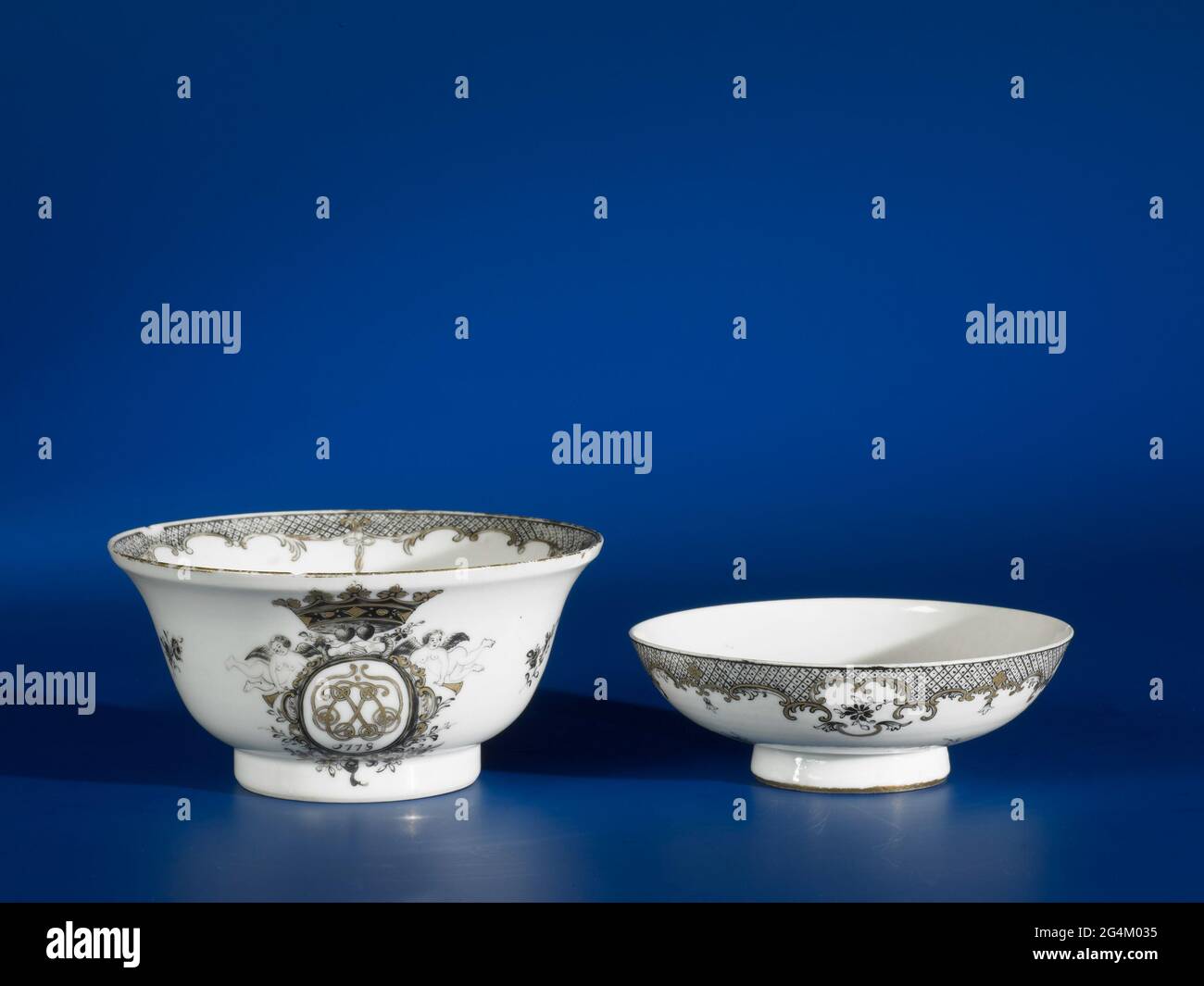. Cloche de porcelaine en forme de cloche, peinte sur le vernis en noir et or. Sur le mur du bol, deux cartouris empis avec du travail bouclés, des guirlandes, une couronne, des mains saccadées et deux anges. Dans une cartouche, les initiales 'EL', dans l'autre 'CS' avec la date '1778' dans les deux dates. Deux branches de fleurs entre les monogrammes; le bord intérieur avec travail de serviette et les airs avec des pinceaux. Deux copeaux sur le bord du bol. Performance européenne à Encre de Chine. Banque D'Images