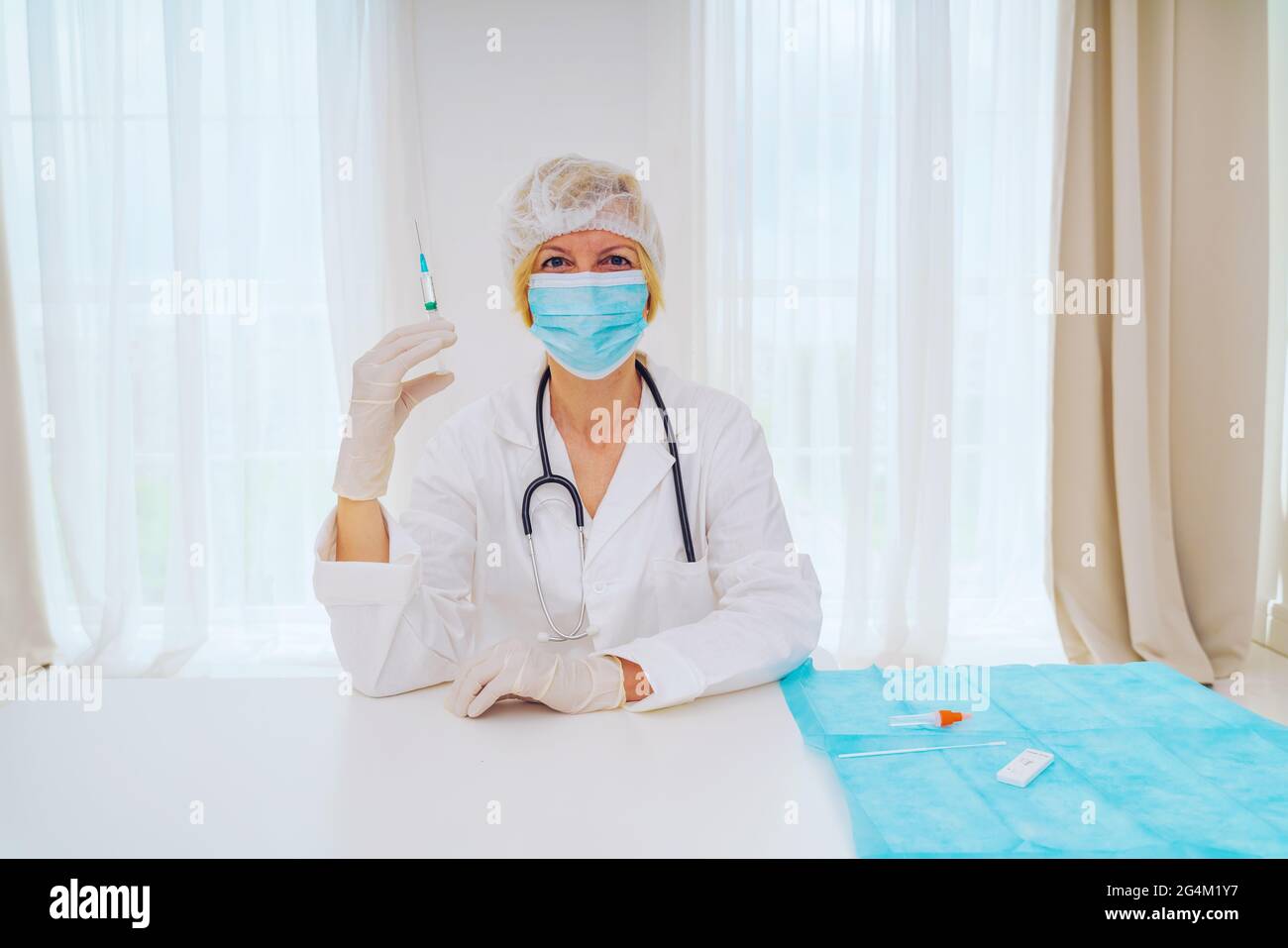 le médecin avec un masque et une seringue est prêt à administrer le vaccin contre le covid 19 Banque D'Images