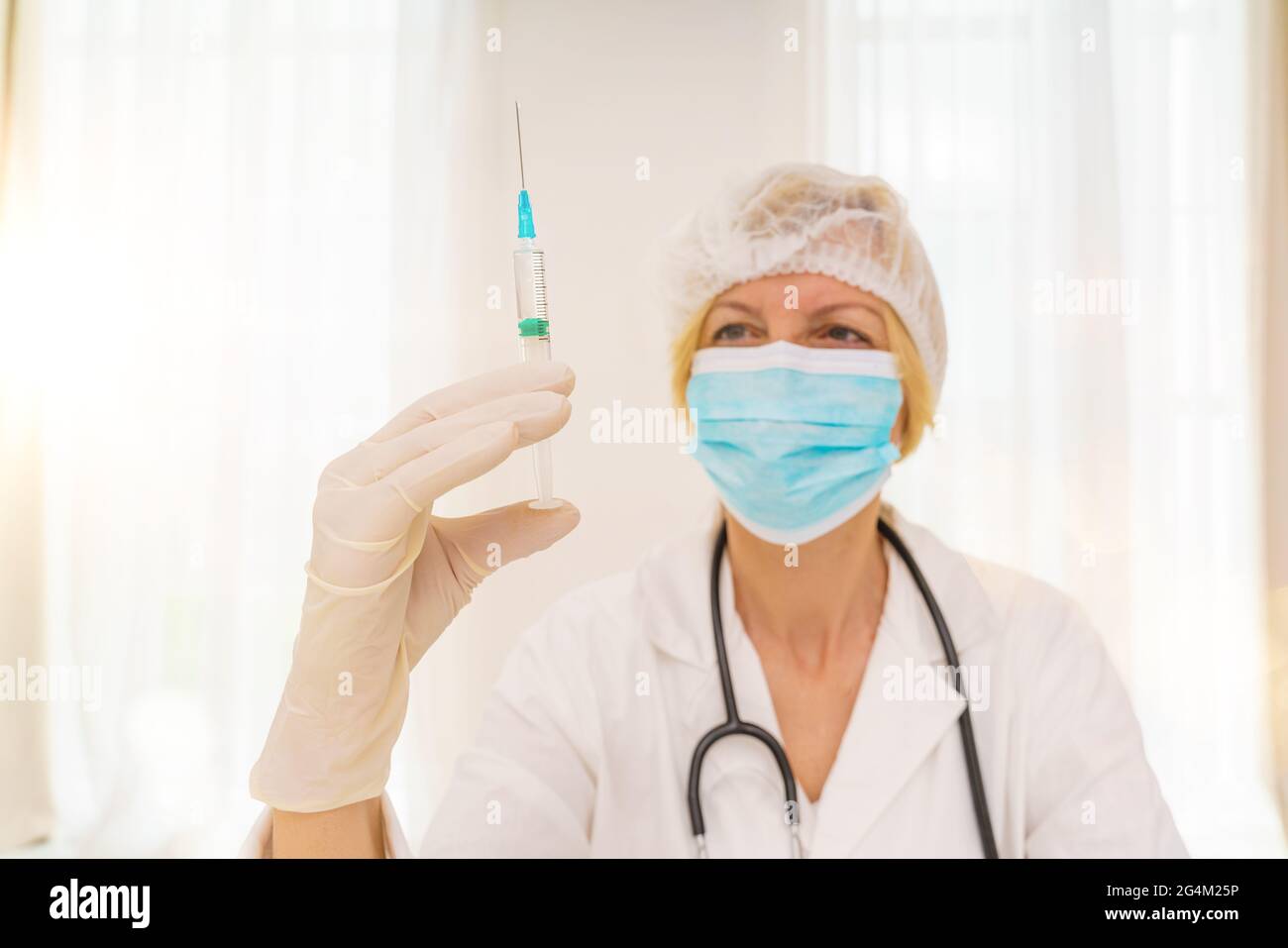 le médecin avec un masque et une seringue est prêt à administrer le vaccin contre le covid 19 Banque D'Images