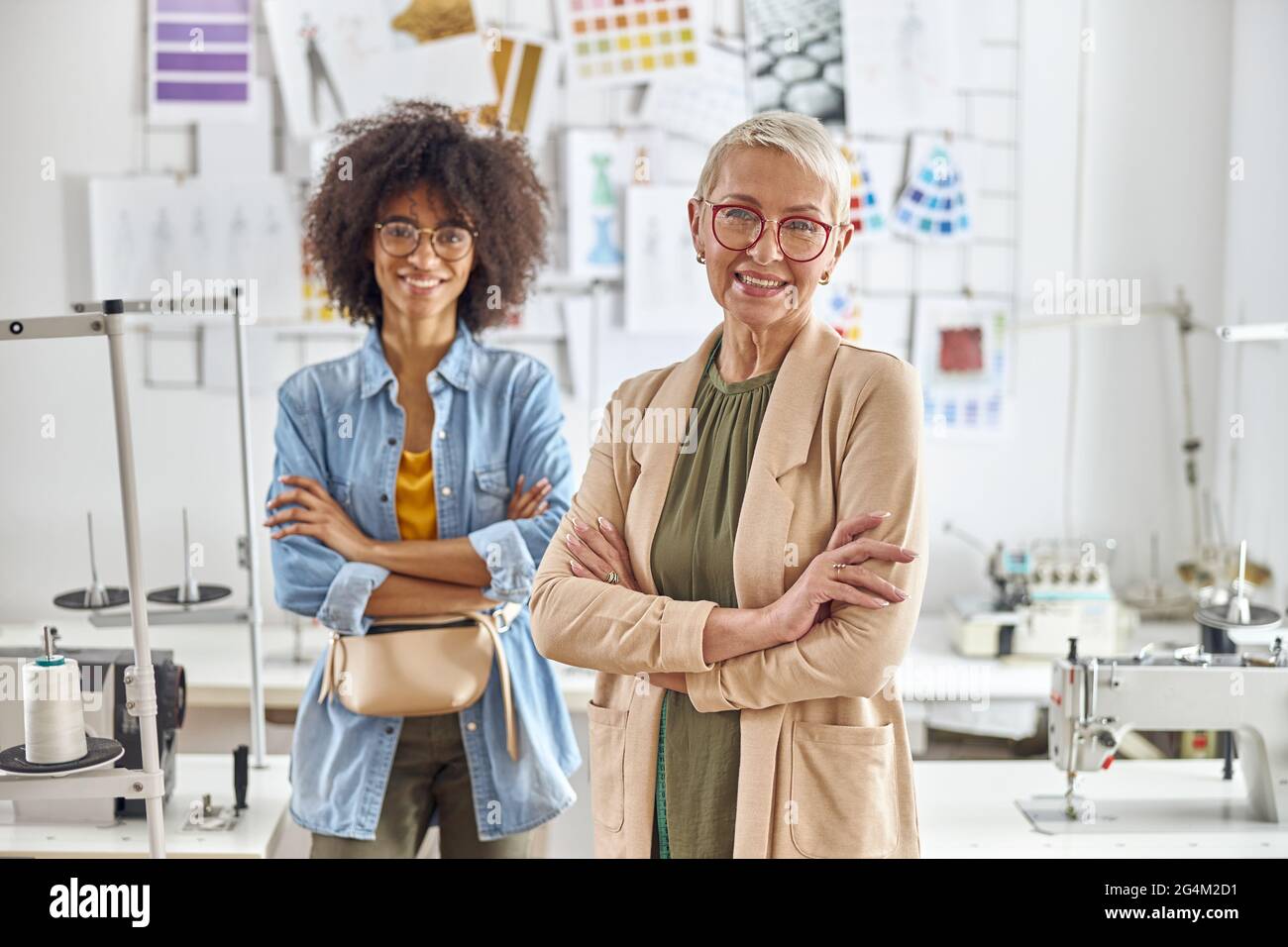 Les couturiers positifs posent pour l'appareil photo ensemble dans un studio de mode léger Banque D'Images