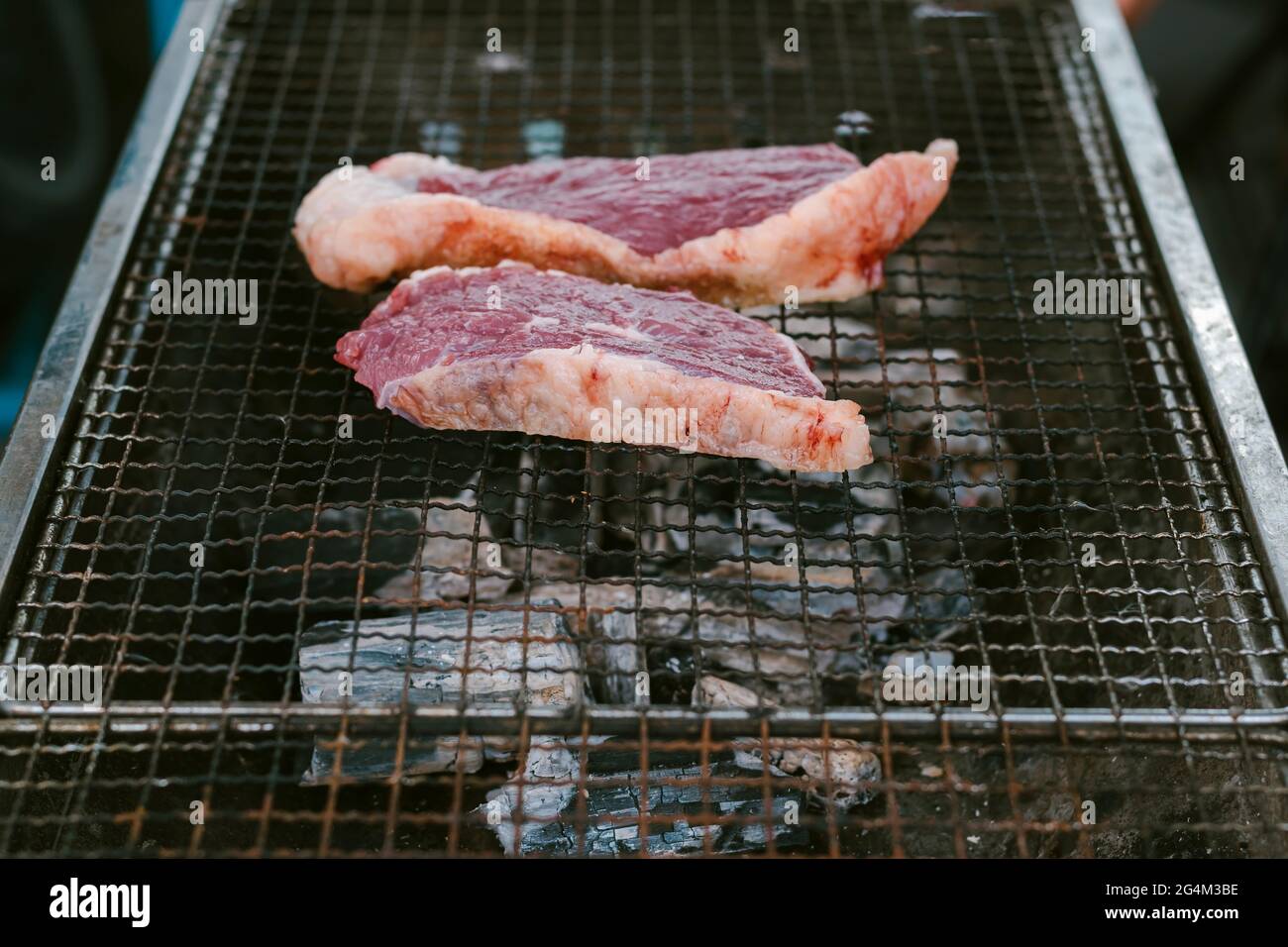Fermer le groupe de faire griller le bœuf sur le gril à charbon de bois pour faire cuire les steaks. Banque D'Images Fermer le groupe de faire griller le bœuf sur le gril à charbon de bois pour faire cuire les steaks. Banque D'Images