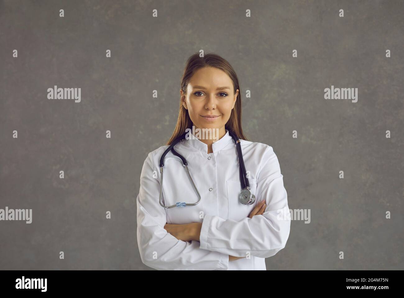 Portrait d'une jeune femme sympathique souriante médecin sur fond de béton gris. Banque D'Images