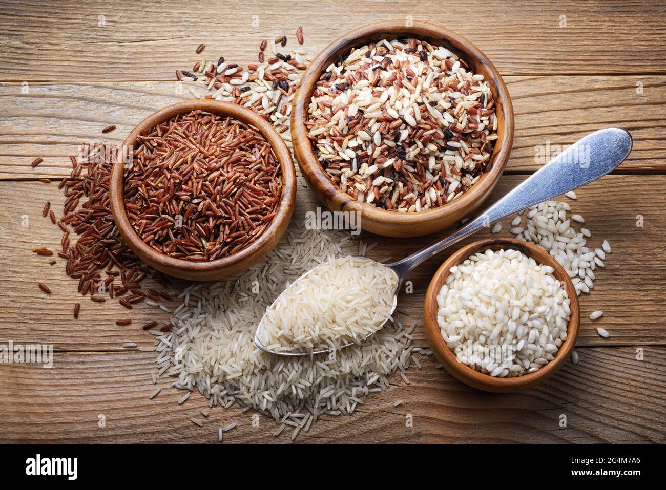 Quatre types de riz : basmati, mélanger le long grain, l'arborio et le riz rouge sur fond de bois. Vue de dessus Banque D'Images