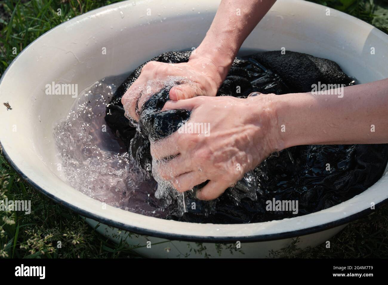 La jeune fille lave les vêtements à la main dans le lavabo. Laver à la main les vêtements dans