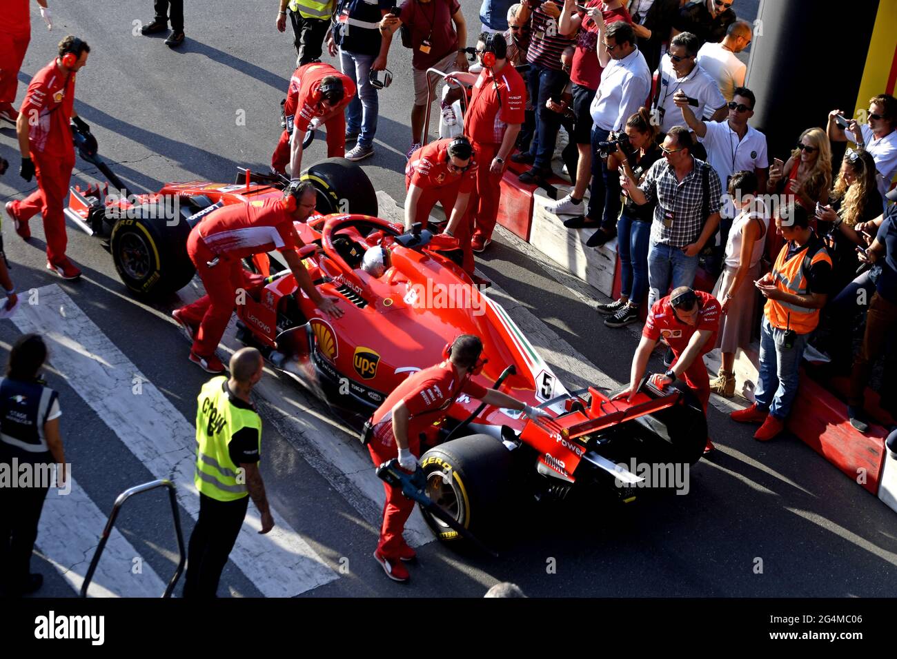 L'équipage du stand de Ferrari travaille autour de la Ferrari Formula One à la boîte de Ferrari, lors d'une exposition à Milan, en Italie. Banque D'Images