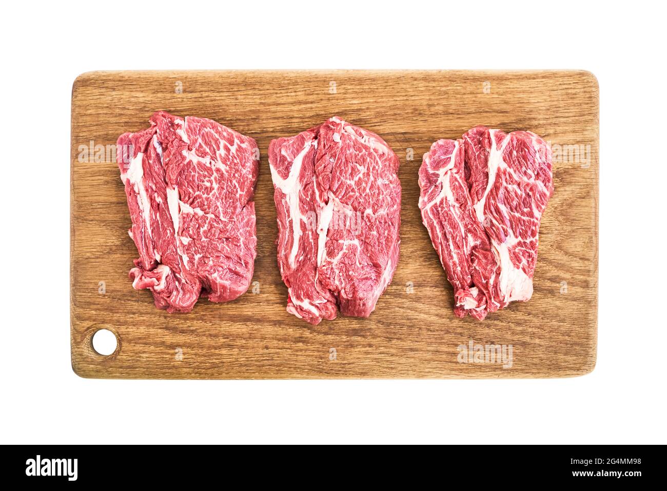 Steaks de bœuf crus sur planche à découper en bois isolés sur fond blanc avec passe-cheveux. Vue de dessus Banque D'Images