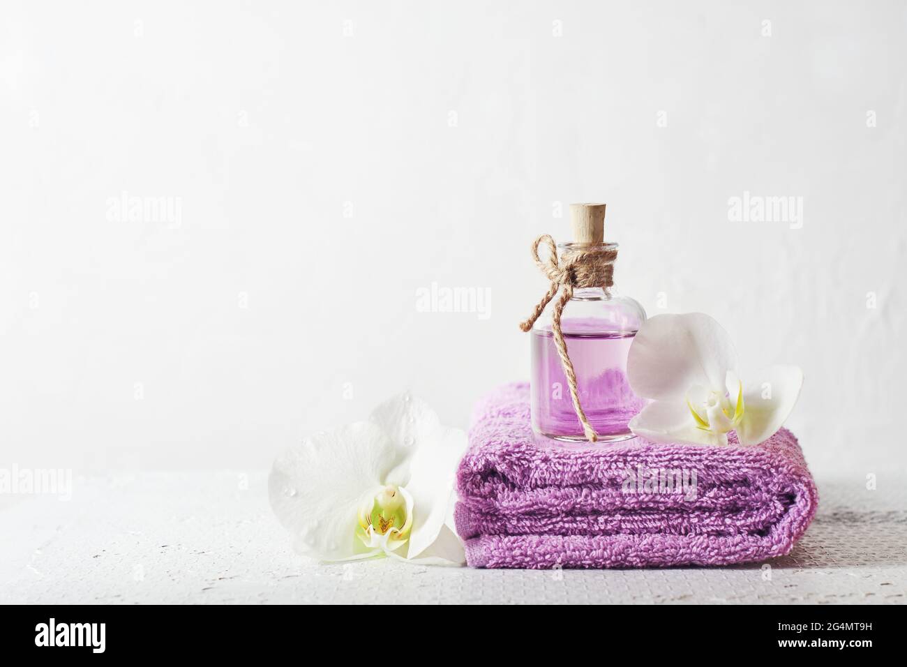 Une bouteille de parfum lilas et de fleurs d'orchidées. Produits cosmétiques aromatiques, soins de spa. Banque D'Images
