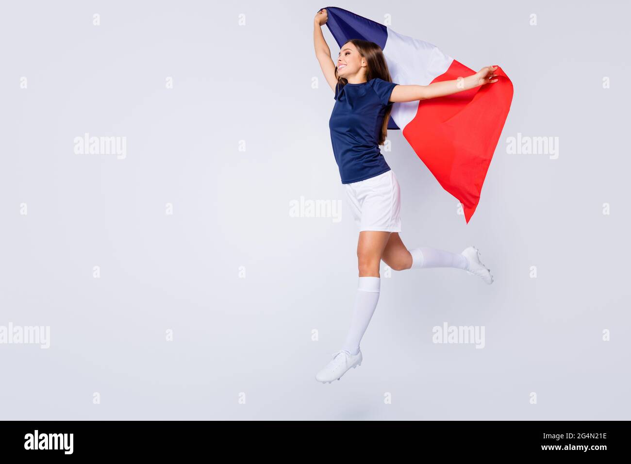 Vue sur toute la longueur du corps belle jolie jolie gaie rêveur fille à cheveux droits jumpant tenant dans la main drapeau français courant marche isolée Banque D'Images