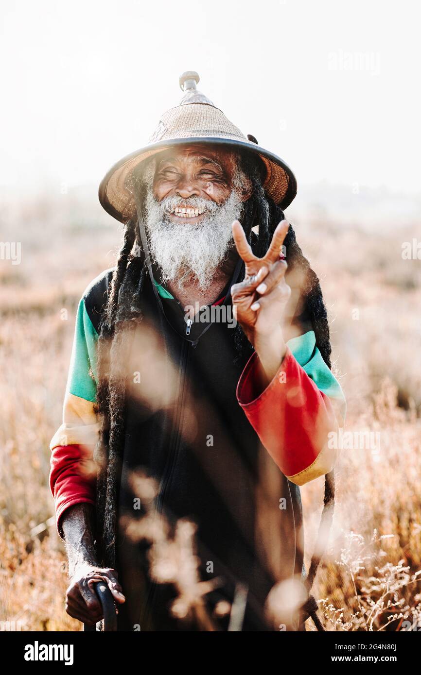 rastafari ethnique ancien gai avec des dreadlocks regardant l'appareil-photo dans un pré sec dans la nature Banque D'Images