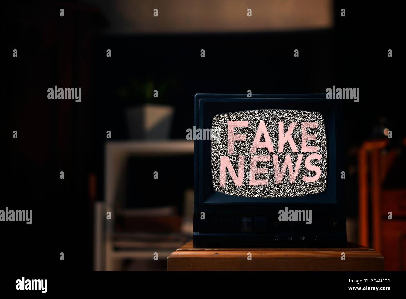 le vieux téléviseur d'époque avec bruit gris à l'écran avec fausses nouvelles texte superposé, debout sur l'étagère à la maison Banque D'Images