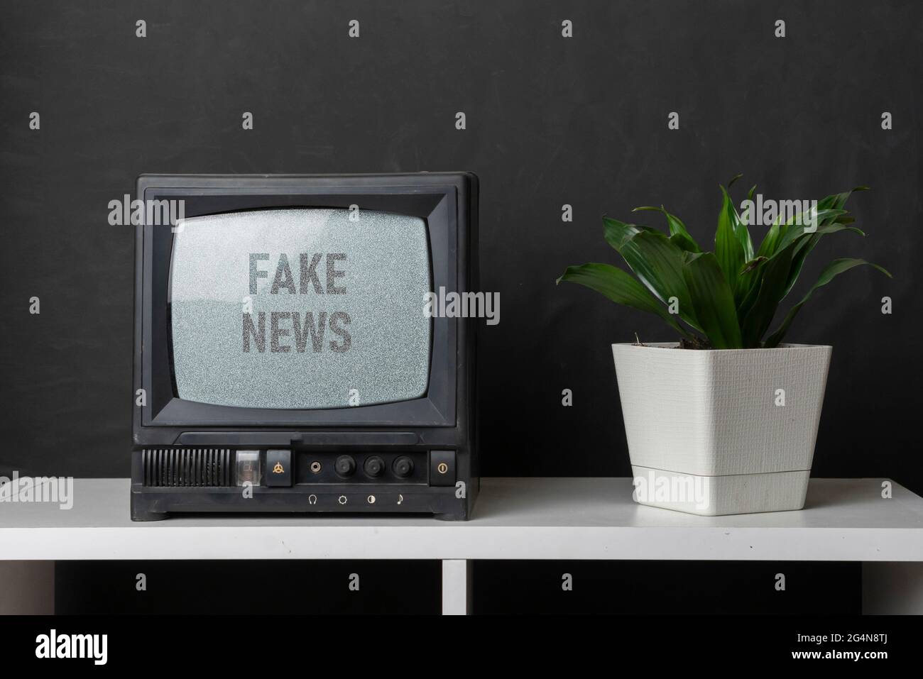 le vieux téléviseur d'époque avec bruit gris à l'écran avec fausses nouvelles texte superposé, debout sur l'étagère à la maison Banque D'Images