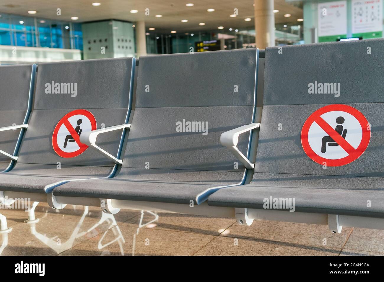 Rangée de sièges vides avec des marqueurs rouges de restriction pour les distances sociales dans le salon de départ de l'aéroport pendant l'épidémie de COVID Banque D'Images