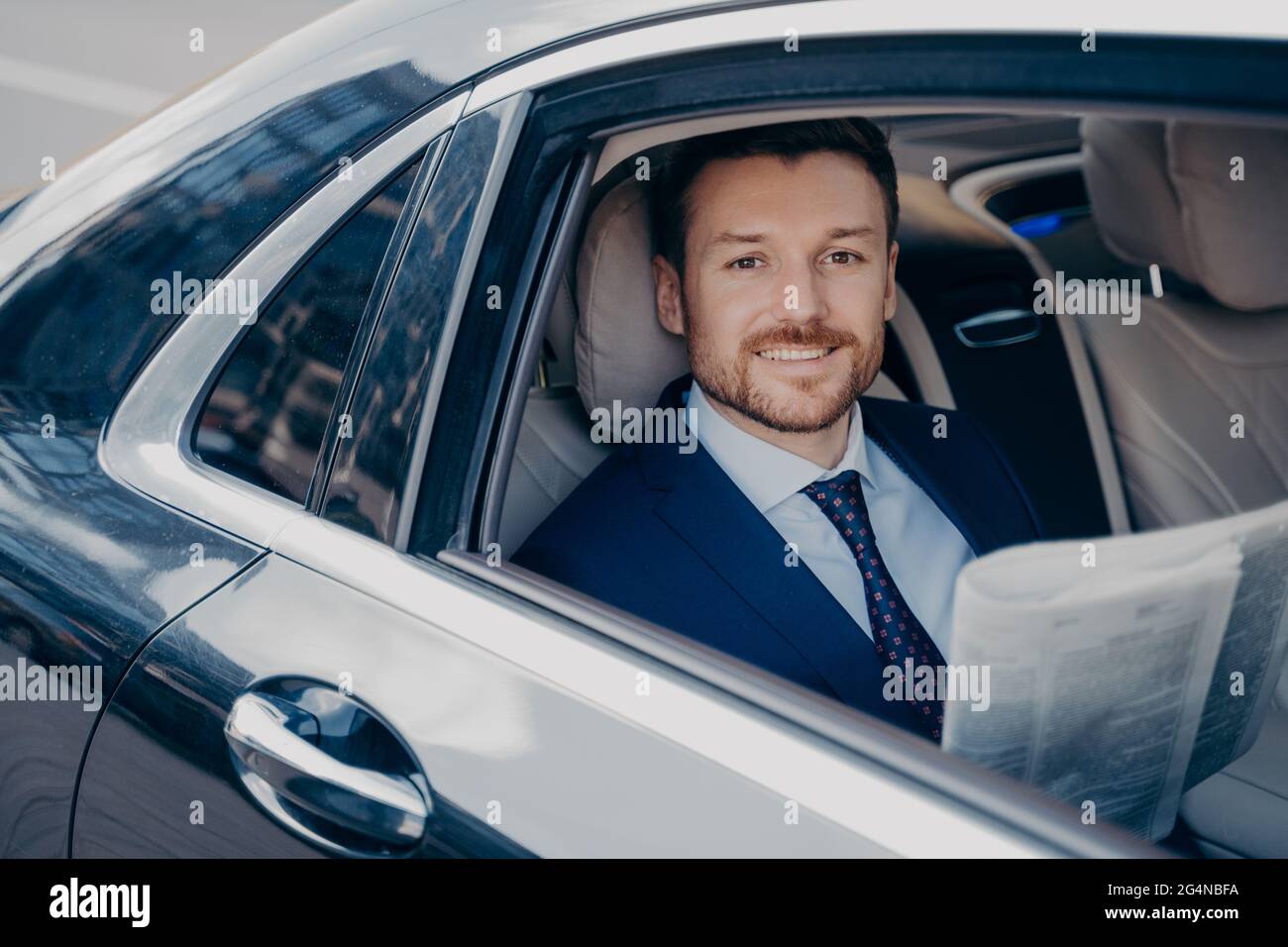 Jeune homme élégant lit journal sur backseat of car Banque D'Images