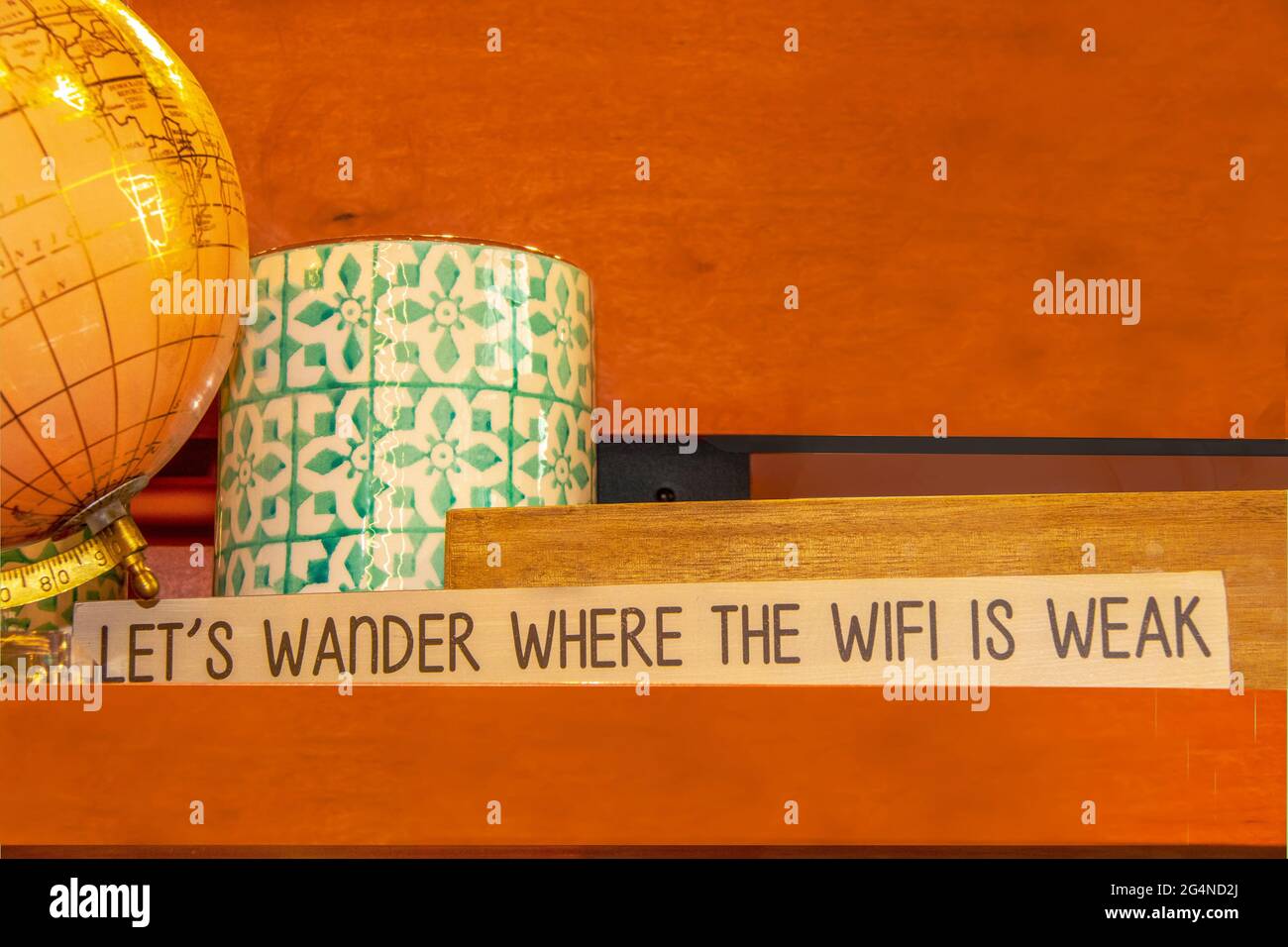 Globe et panneau décoratifs qui vous permettent de vous promener là où le WIFI est faible sur une étagère avec des planches orange aléatoires et de la place pour la copie Banque D'Images