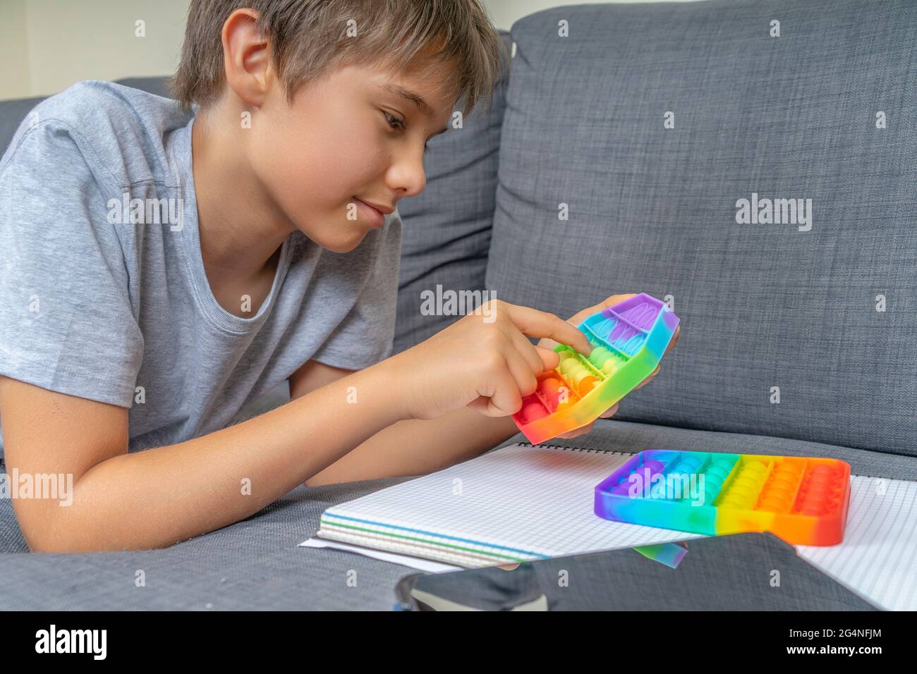 Garçon adolescent allongé sur le canapé et jouant avec le jouet de violon  de pop sensoriel après avoir appris avec une tablette, faire des devoirs  Photo Stock - Alamy