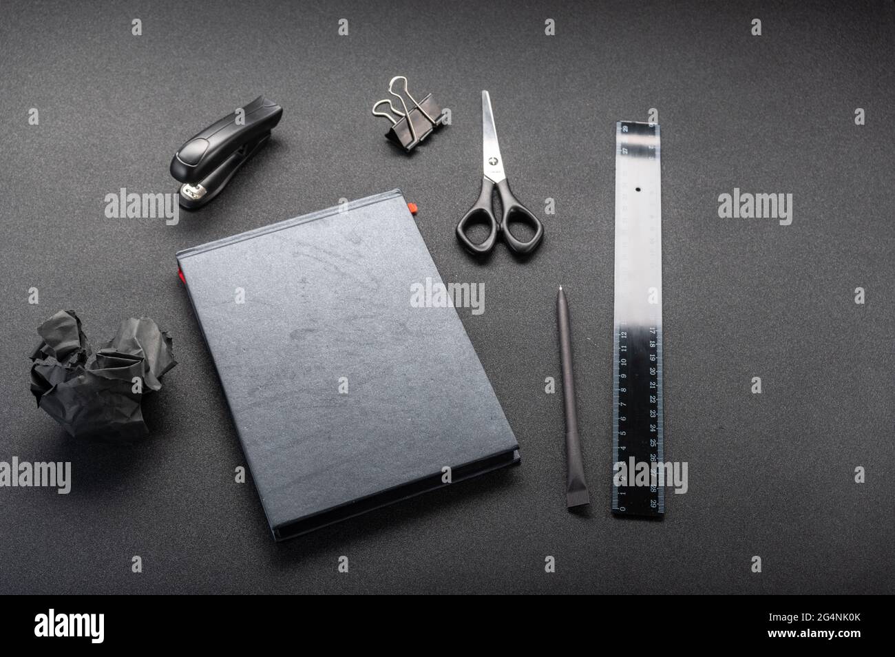 Fournitures de bureau noires sur une table noire. Règle noire et bloc-notes noir. Banque D'Images
