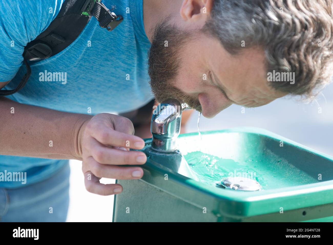 Un gars assoiffé boit de l'eau de la fontaine qui se désaltérant soif, hydratation Banque D'Images