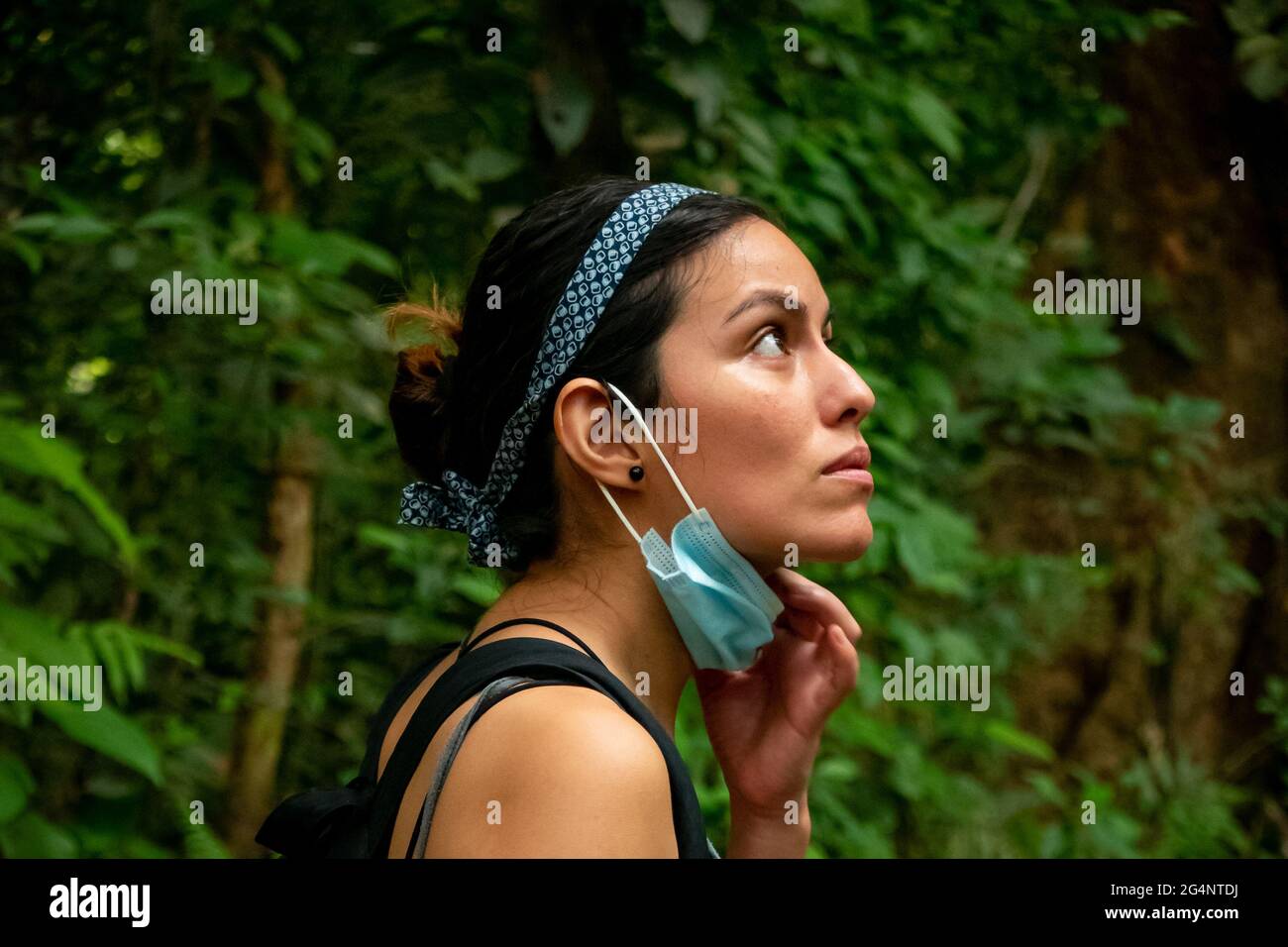 Femme latine marchant au milieu de la nature en utilisant un masque Covid-19 Banque D'Images