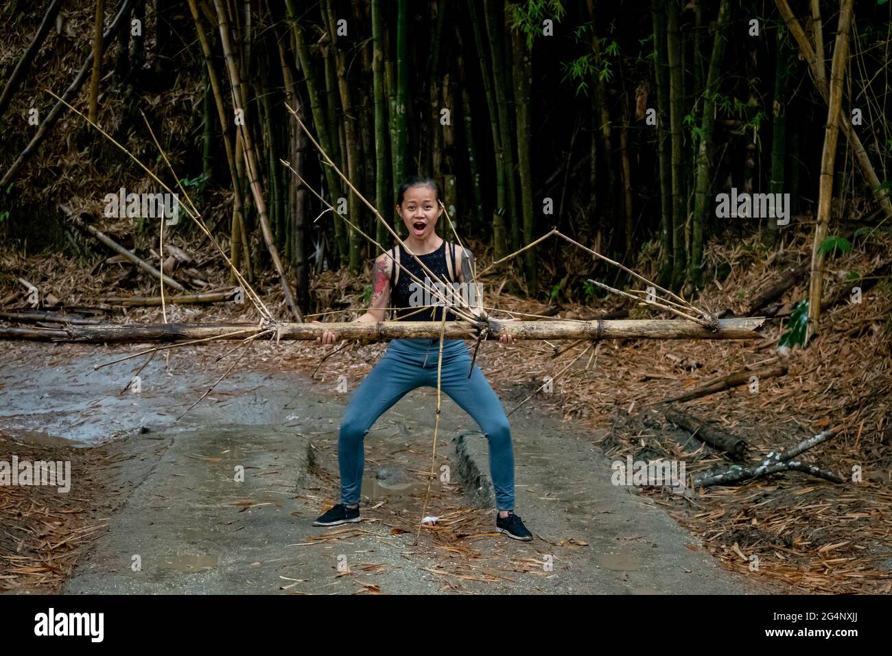 Asiatic Woman lève un bambou dans une route sèche à Minca, Colombie Banque D'Images