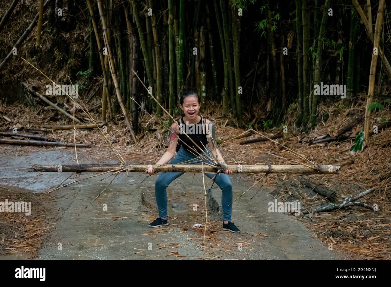 Asiatic Woman lève un bambou dans une route sèche à Minca, Colombie Banque D'Images