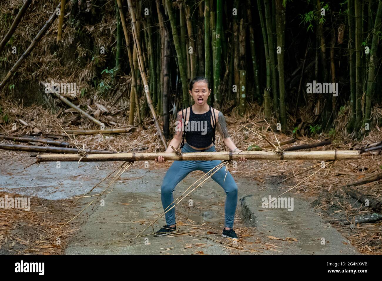 Asiatic Woman lève un bambou dans une route sèche à Minca, Colombie Banque D'Images