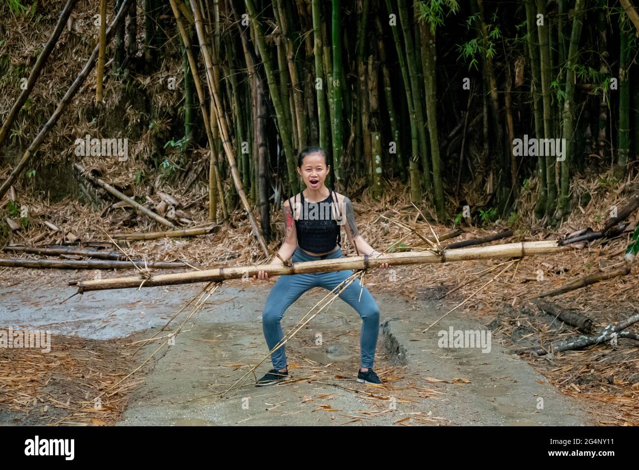Asiatic Woman lève un bambou dans une route sèche à Minca, Colombie Banque D'Images