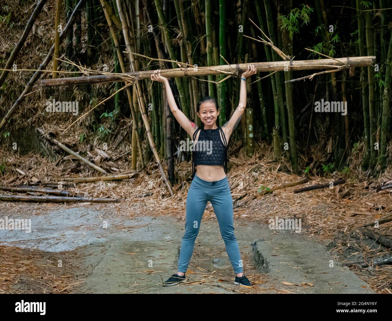 Asiatic Woman lève un bambou dans une route sèche à Minca, Colombie Banque D'Images