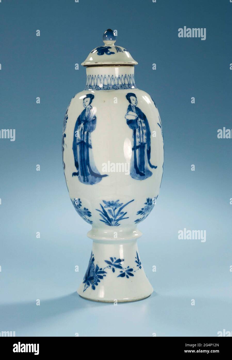 . Bouchon de couvercle en porcelaine en forme d'œuf au pied haut avec épaississement annulaire, peint en bleu sous-glaçure. Sur le mur six compartiments modélisés avec une dame chinoise (longues poux) ou un vase de fleur (Lotus, chrysanthème); en dessous de six compartiments modélisés plus petits avec des variétés de fleurs et de fruits; le pied avec une fleur et un fruittak; sur le cou un bracelet avec motif de Meander au-dessus duquel les feuilles pointues; Le couvercle avec des objets de valeur (diamant, perle, artimisialabra) entre lesquels trois caractères chinois 'Zhou', signification significative. Bleu blanc. Banque D'Images