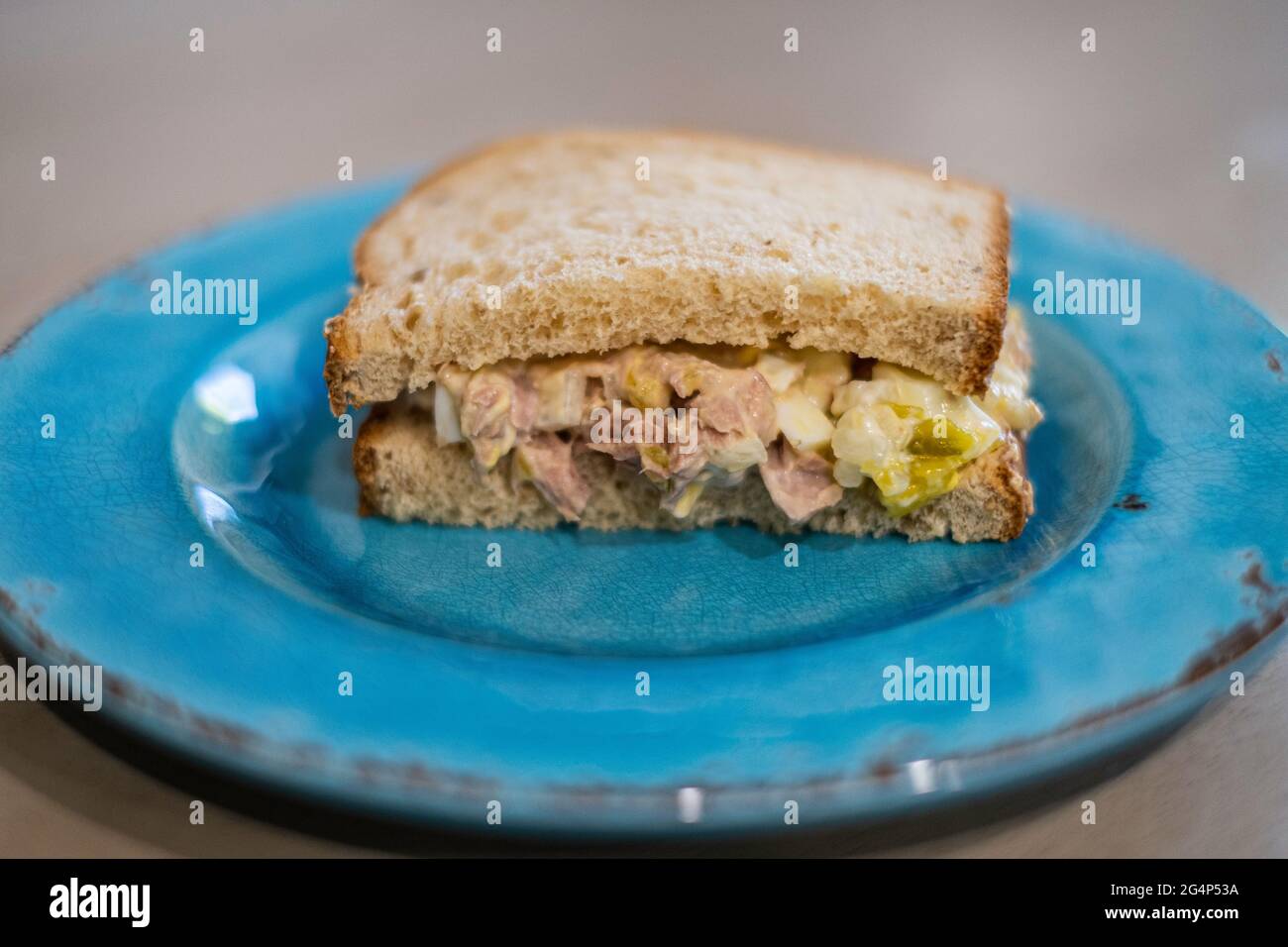 La moitié d'un sandwich de thon avec du pain d'avoine sur une assiette bleue. Gros plan. Banque D'Images