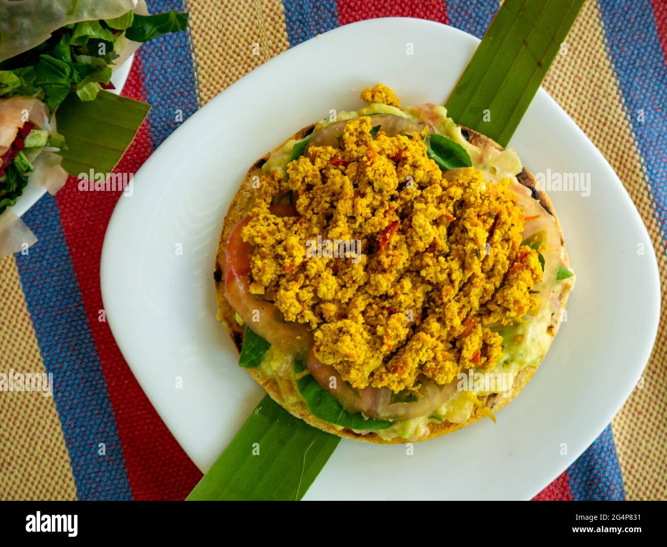 En-cas colombien typique Arepa farci de tomates, avocat et tofu servi sur une assiette blanche Banque D'Images