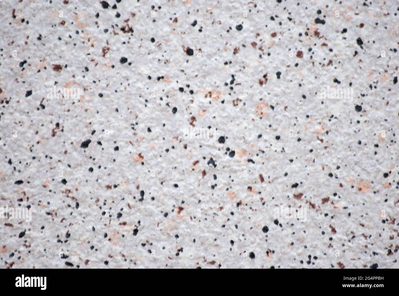 Granit blanc avec petites taches orange et noir, gros plan de la surface en pierre naturelle. Arrière-plan, motif, texture. Banque D'Images