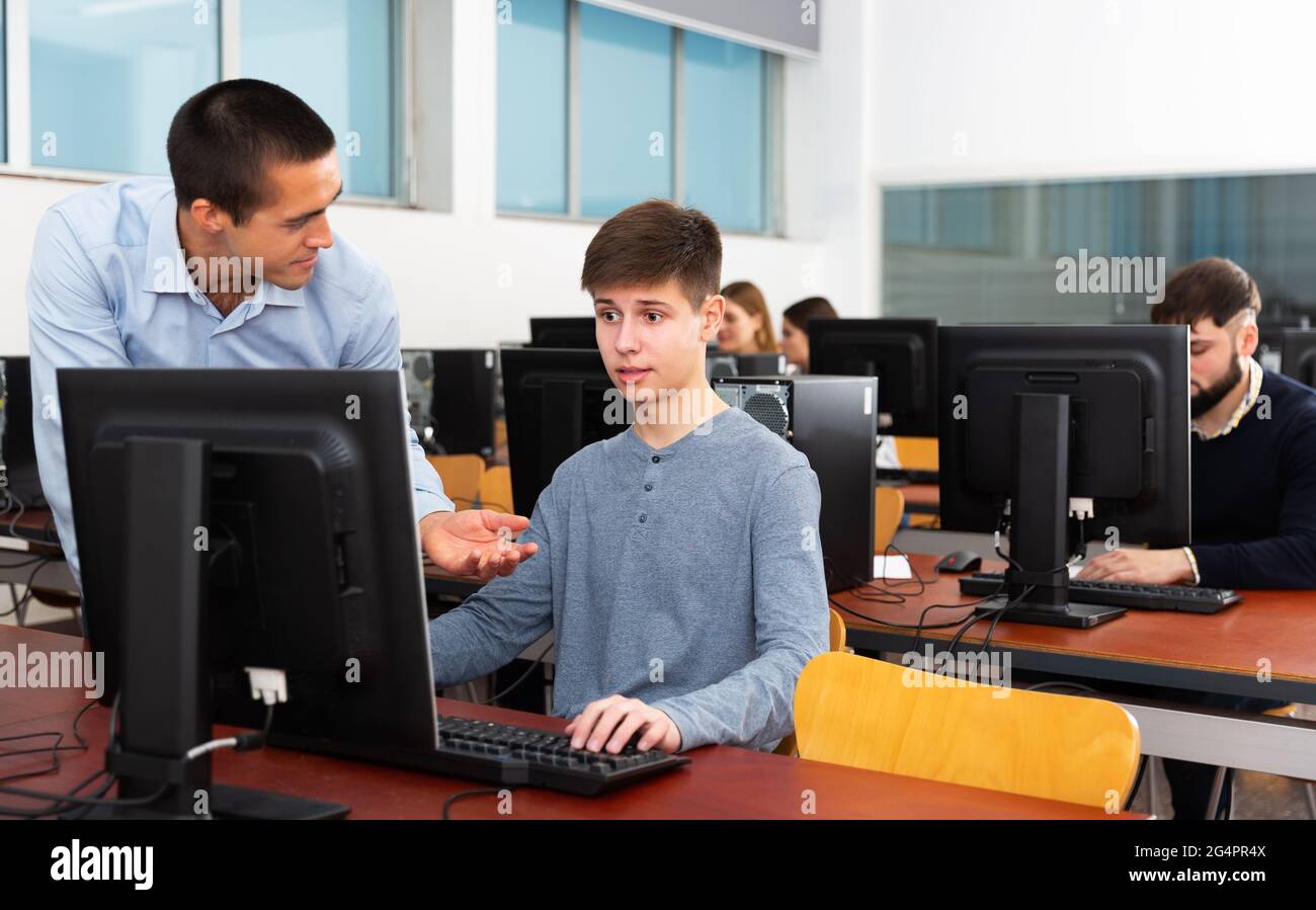 Enseignant travaillant avec l'étudiant en classe informatique Banque D'Images